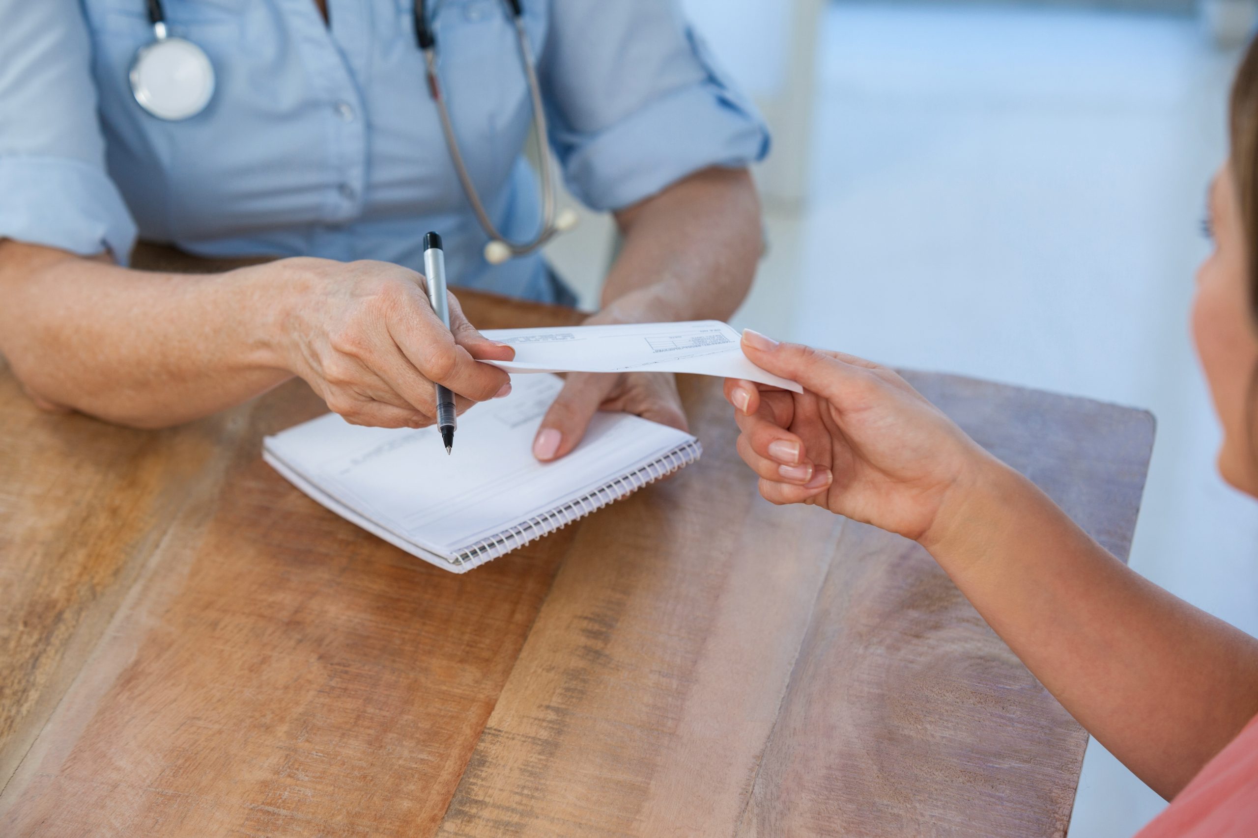 Doctor giving a prescription to her patient in medical office